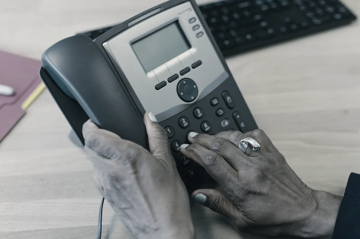 Mains composant un numéro sur un téléphone de bureau
